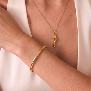Bracciale schiava tondo in oro 18 carati Armando Poggi indossato al polso con charm corno grande coordinato.
